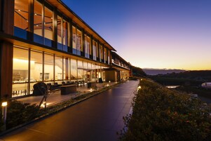 Un hotel moderno con amplios ventanales, mobiliario exterior y vistas al paisaje.
