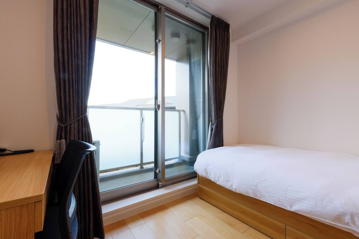 Ein Hotelzimmer mit einem Bett, einem Schreibtisch und einer Glasschiebetür, die auf einen Balkon führt.