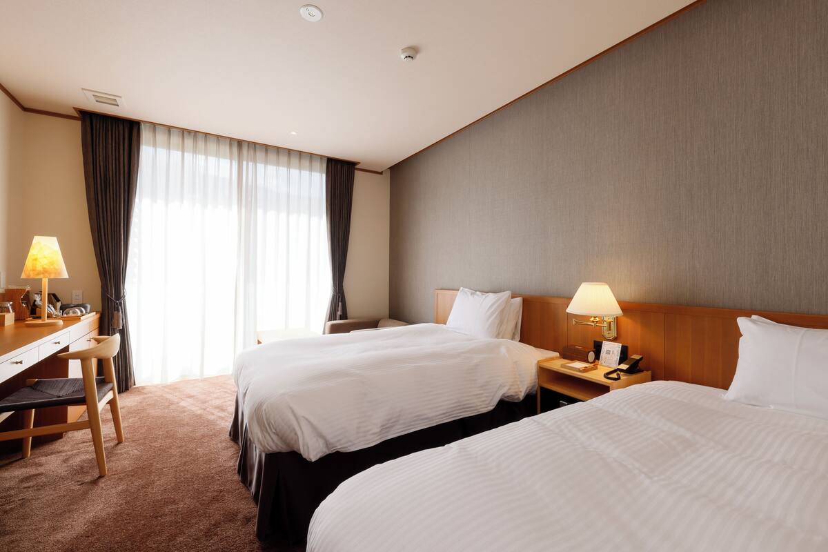 Ein Hotelzimmer mit zwei Betten, einem Schreibtisch und einem Stuhl.