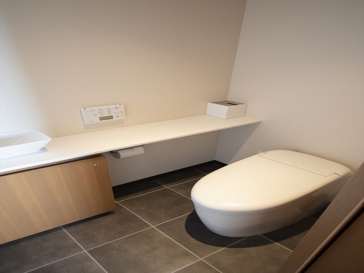 A small, modern bathroom with a toilet, a sink, and a towel rack.