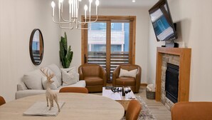 Ein Wohnzimmer mit Kamin, Ledersofas, einem Esstisch und einem an der Wand befestigten Fernseher.