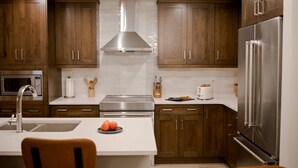 Eine moderne Küche mit Holzschränken, Edelstahlgeräten und einer weißen Arbeitsplatte.