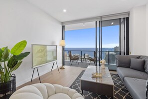 Relax in a spacious living room with a city and sea view, featuring a comfortable seating area and a glass coffee table.