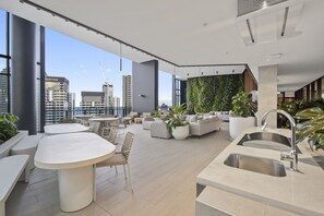 Enjoy expansive city views from the high ceiling and large windows in this open-plan living area, featuring a kitchen and vertical garden wall.