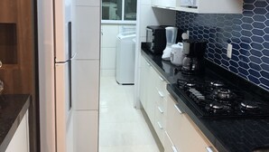 A modern kitchen with white cabinets, a black countertop, and a gas stove.