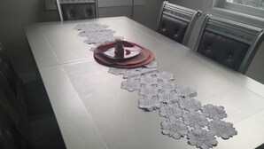 Una mesa de comedor con un camino de mesa floral y una pila de platos.