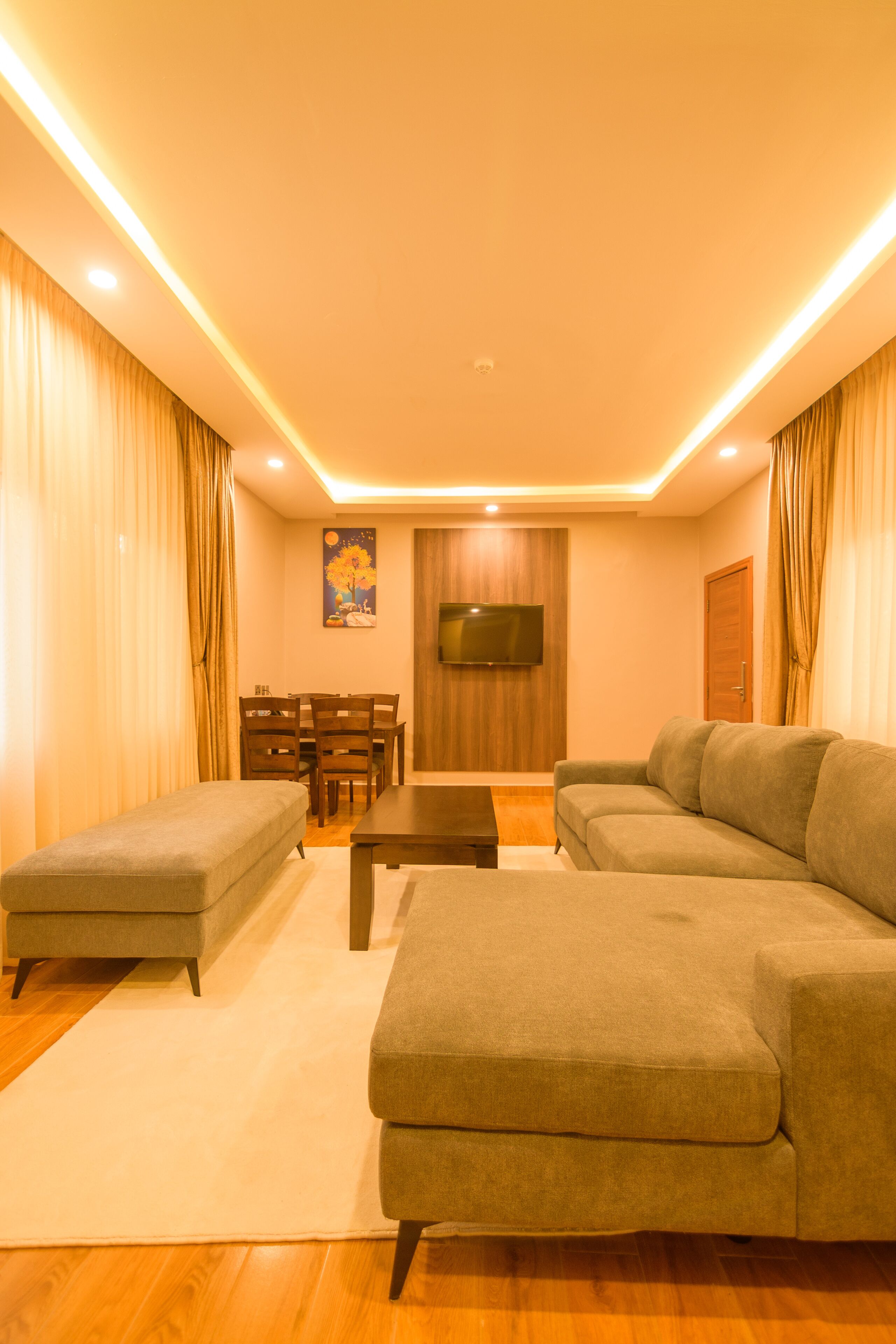 A modern living room with a sofa, ottoman, and a flat-screen TV mounted on the wall.