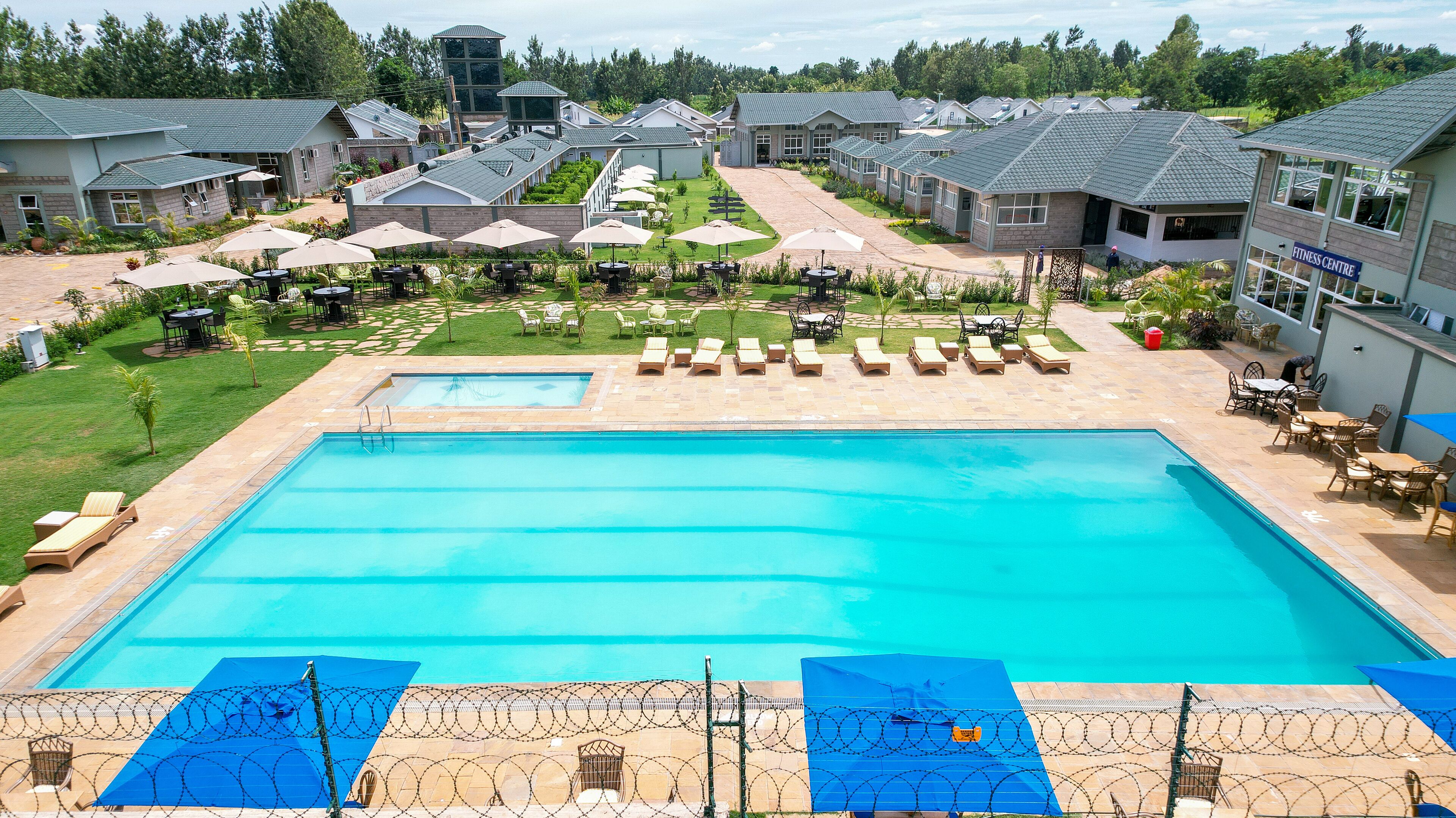 A swimming pool with lounge chairs and umbrellas, surrounded by a landscaped garden and residential buildings.