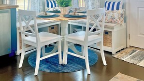 Un comedor con una mesa redonda, sillas blancas y detalles azules.