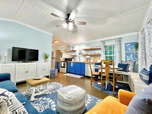 Relax in this open-plan living space with a kitchen area, featuring a dining table, sofa, and television.