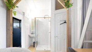 Een moderne badkamer met een douchecabine van glas, een wit wastafelmeubel en een houten deur.