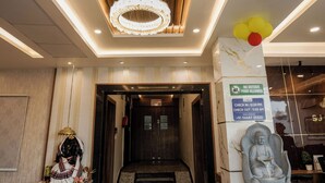 A reception area with a wooden ceiling, a chandelier, a statue, and a sign indicating no outside food allowed.