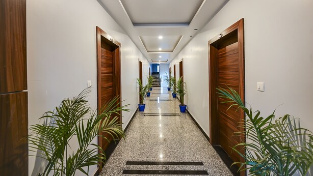 A hallway with wooden doors, potted plants, and a marble floor.
