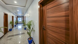 A hallway with wooden doors, potted plants, and a number sign.