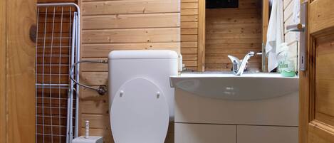 A wooden cabin bathroom with a toilet, sink, and a mirror above the sink.