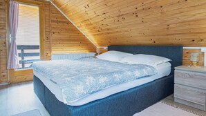 Une chambre avec un plafond en bois, un lit avec un matelas bleu, une table de chevet et une fenêtre avec des rideaux.
