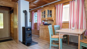 L’intérieur chaleureux d’un chalet avec un poêle à bois, des meubles en bois et des rideaux à rayures.