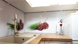 Une cuisine équipée d’un évier, d’un plan de travail en bois, de meubles blancs et d’un porte-verres à vin fixé au mur.