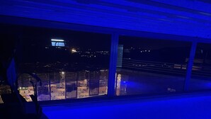 Zona de piscina interior poc il·luminada amb vista a la ciutat de nit.