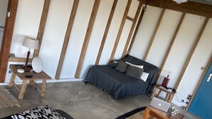 A bedroom with a bed, bedside table, lamp, and a laptop on a wooden table.