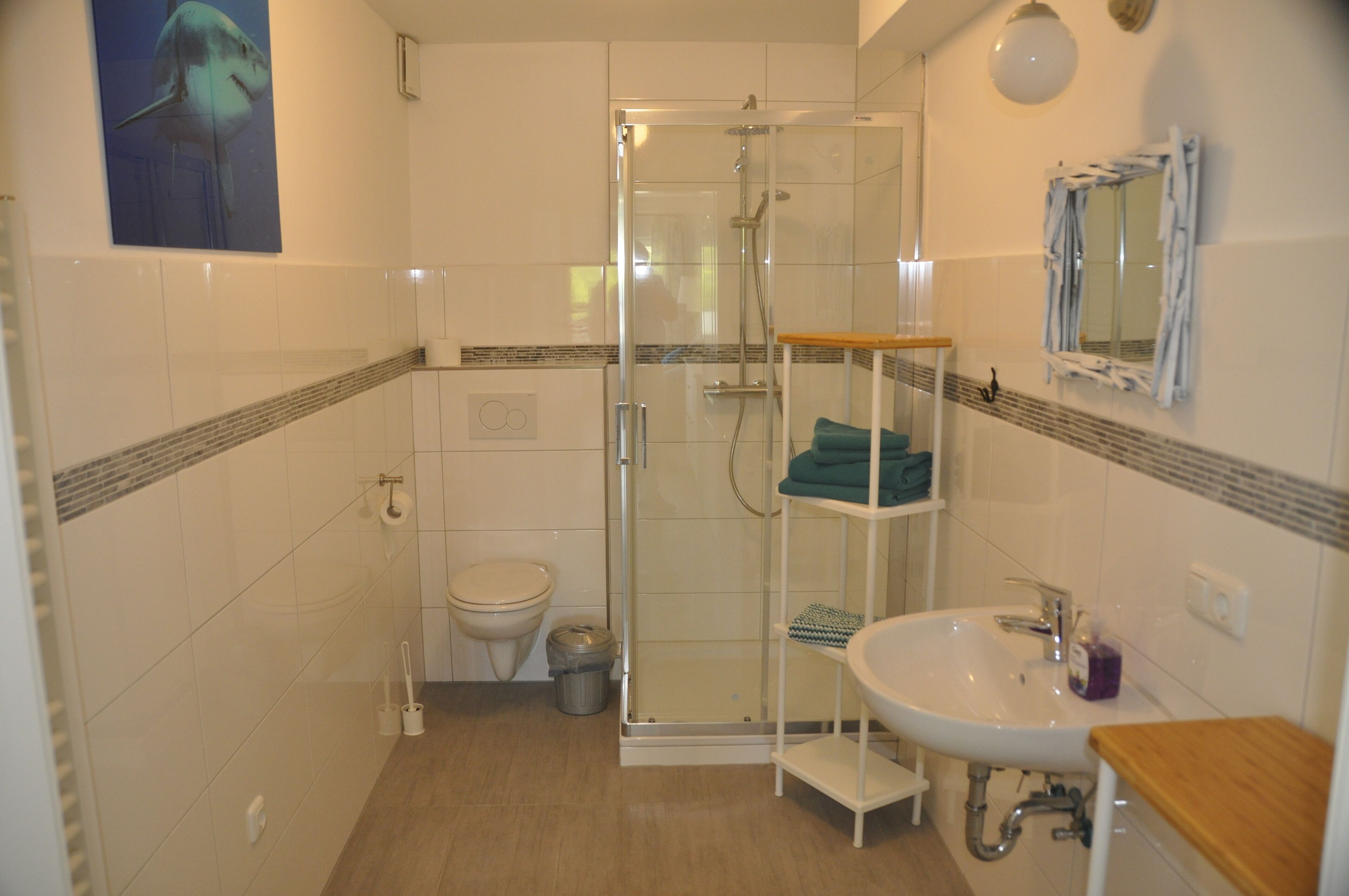A bathroom with a glass-enclosed shower, a white sink, and a toilet.
