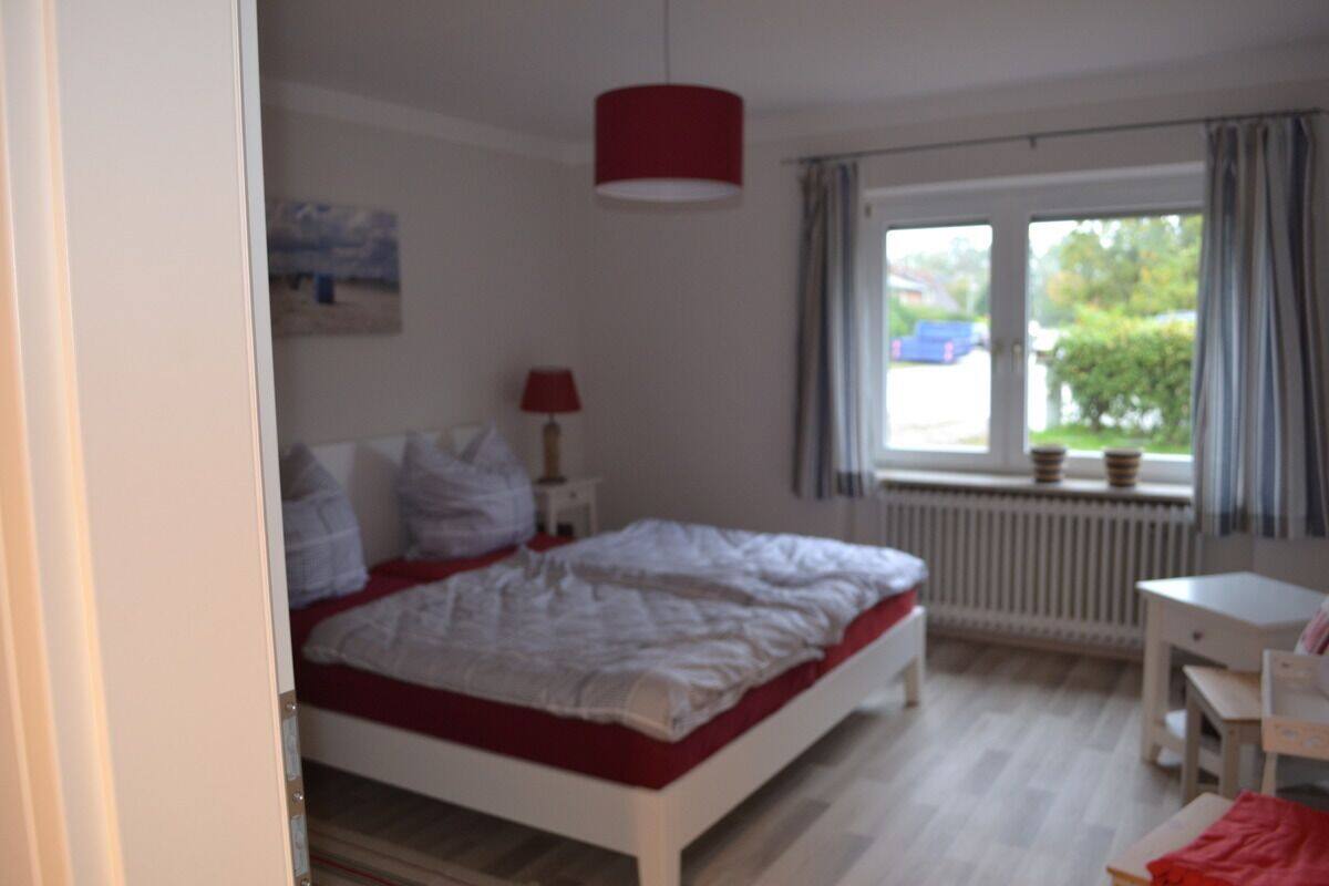 Une chambre à coucher avec un lit, un bureau et une fenêtre avec des rideaux.