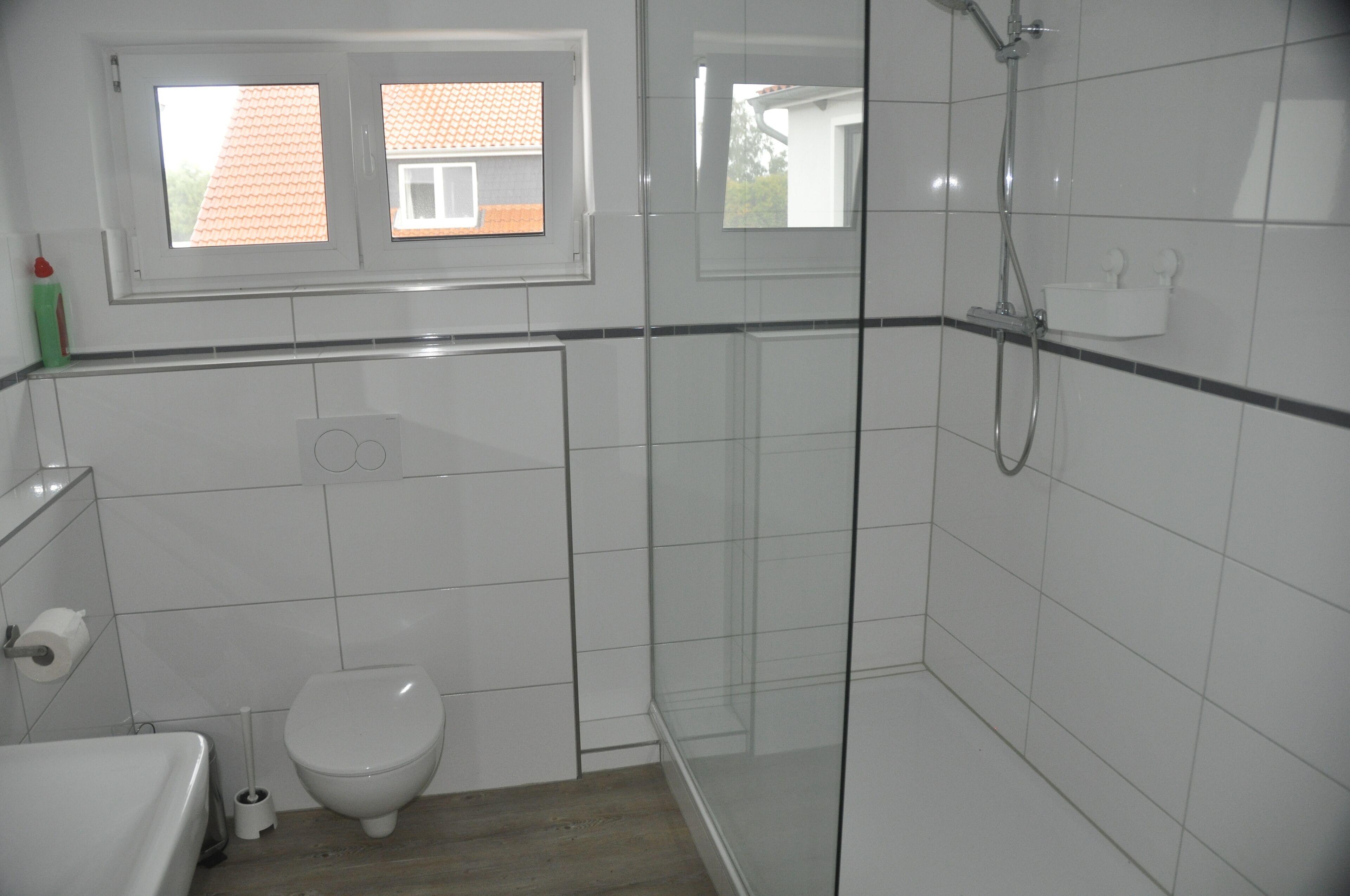 A modern bathroom with a toilet, sink, and glass-enclosed shower area.