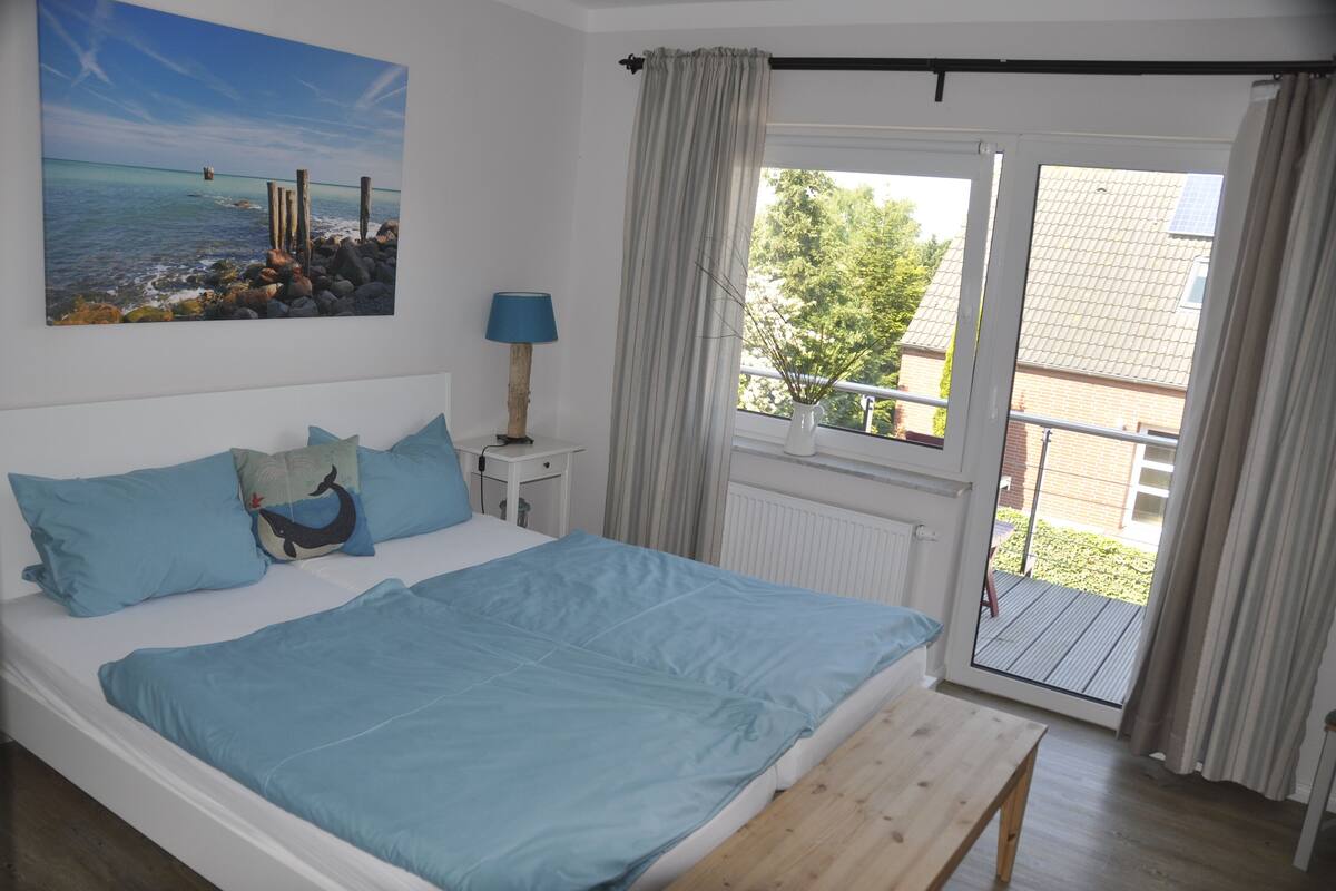 Une chambre à coucher comprenant un lit, une table de chevet, une lampe et une vue sur l’extérieur grâce à une porte coulissante.