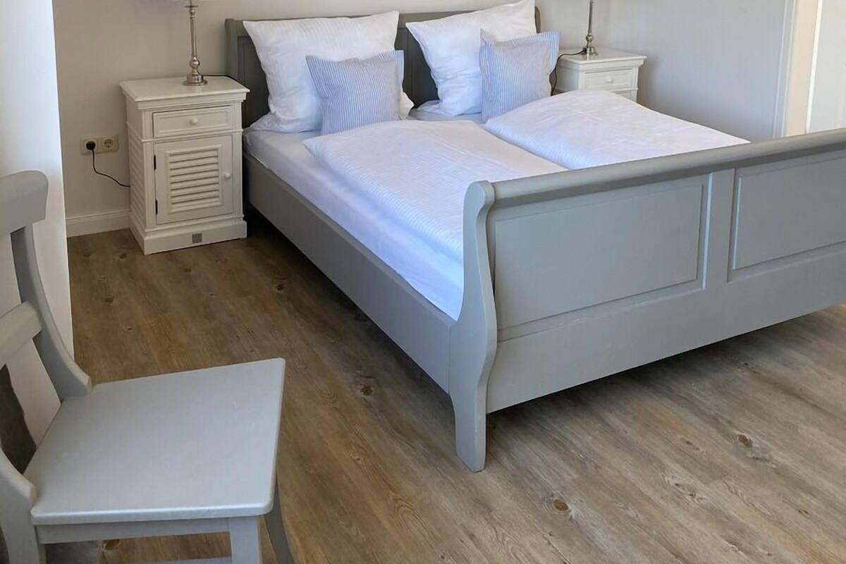 Une chambre à coucher comprenant un lit, deux tables de chevet, une chaise et une petite table.