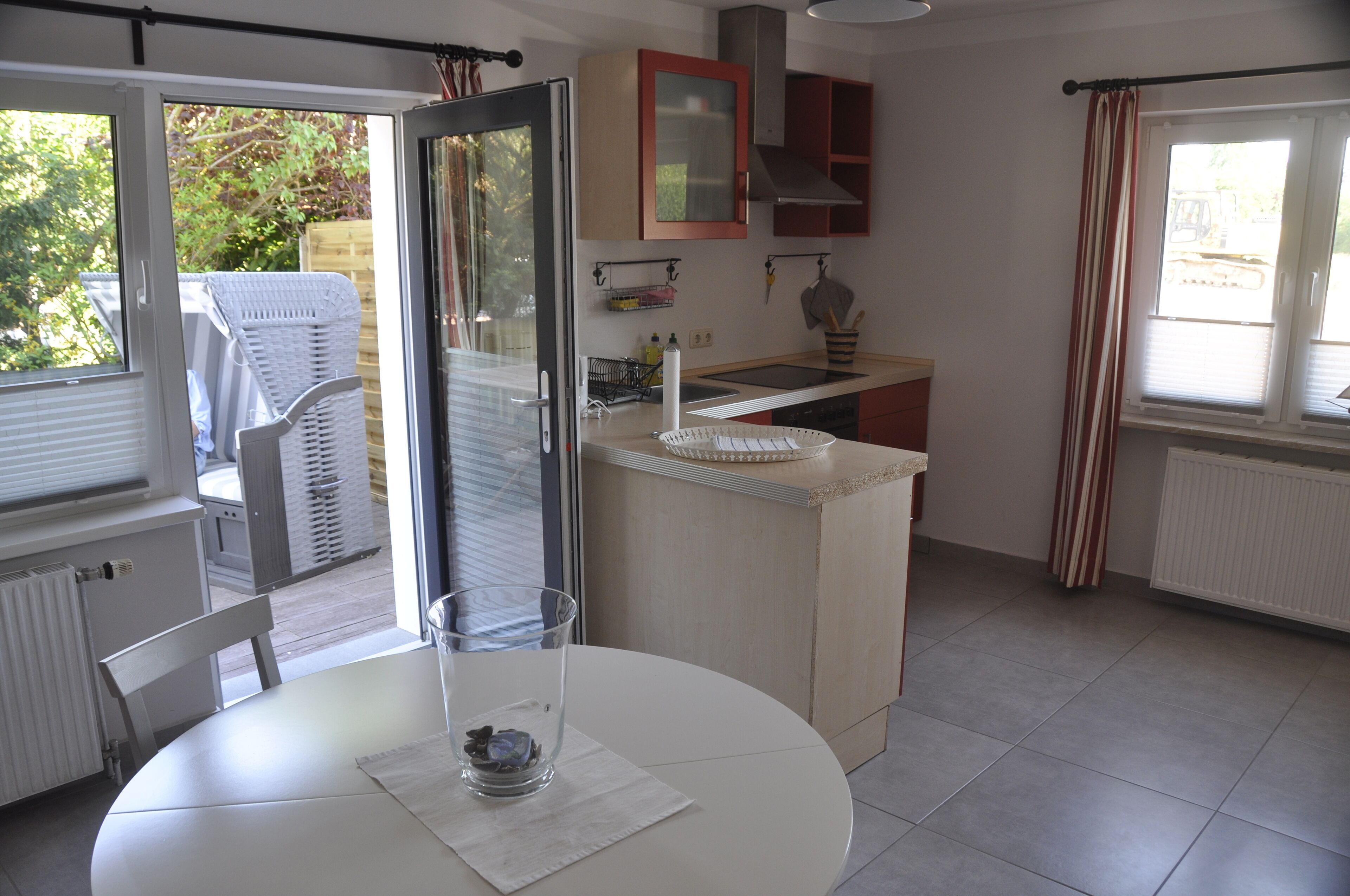 Una cocina con comedor, una mesa blanca y un vaso de agua sobre la mesa.