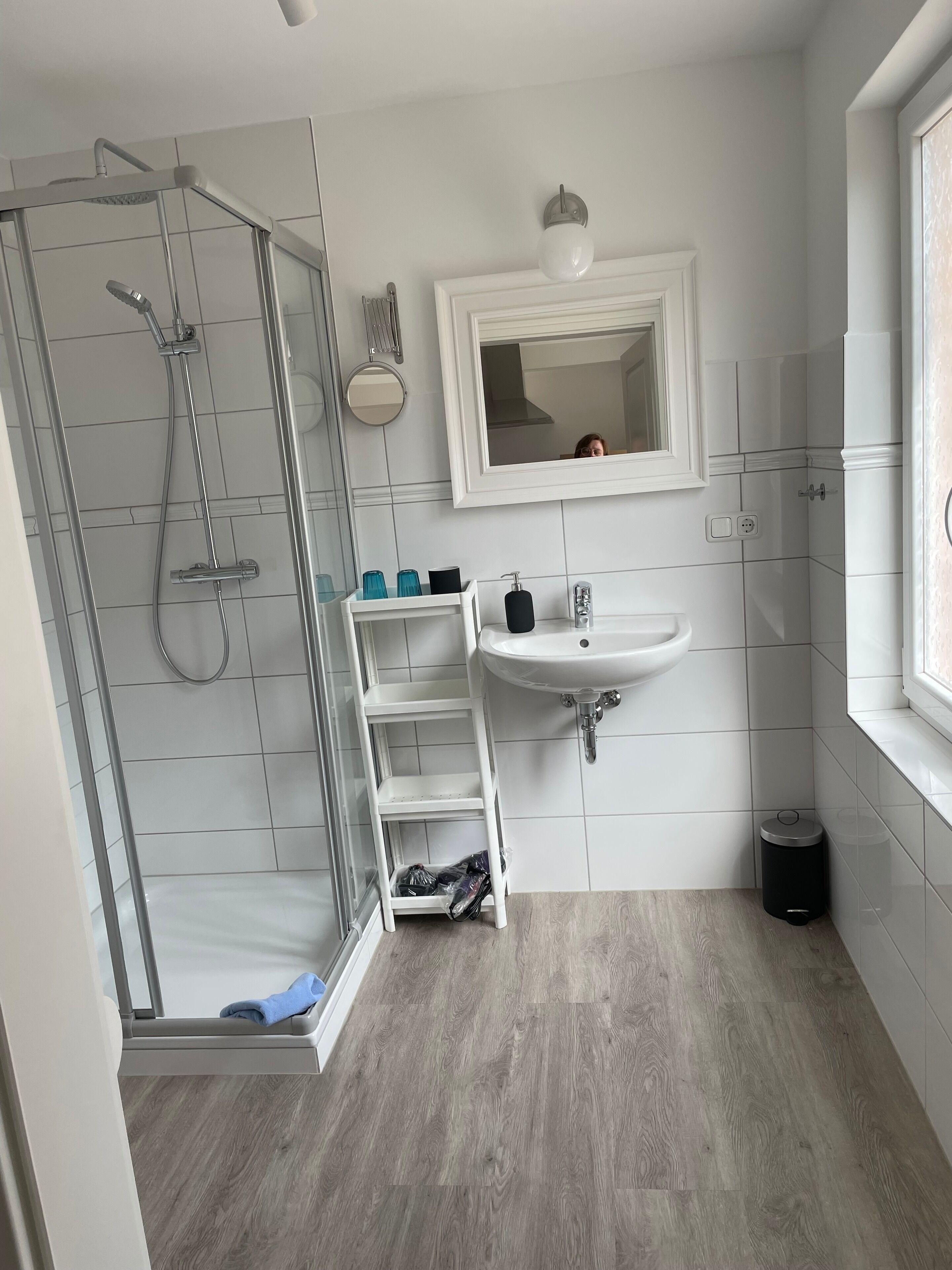 Ein modernes Badezimmer mit einer Duschkabine aus Glas, einem weißen Waschbecken und einem Spiegel darüber.