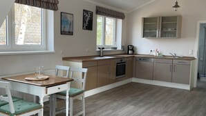 Une cuisine spacieuse avec un coin repas, des poutres apparentes en bois au plafond et de grandes fenêtres.