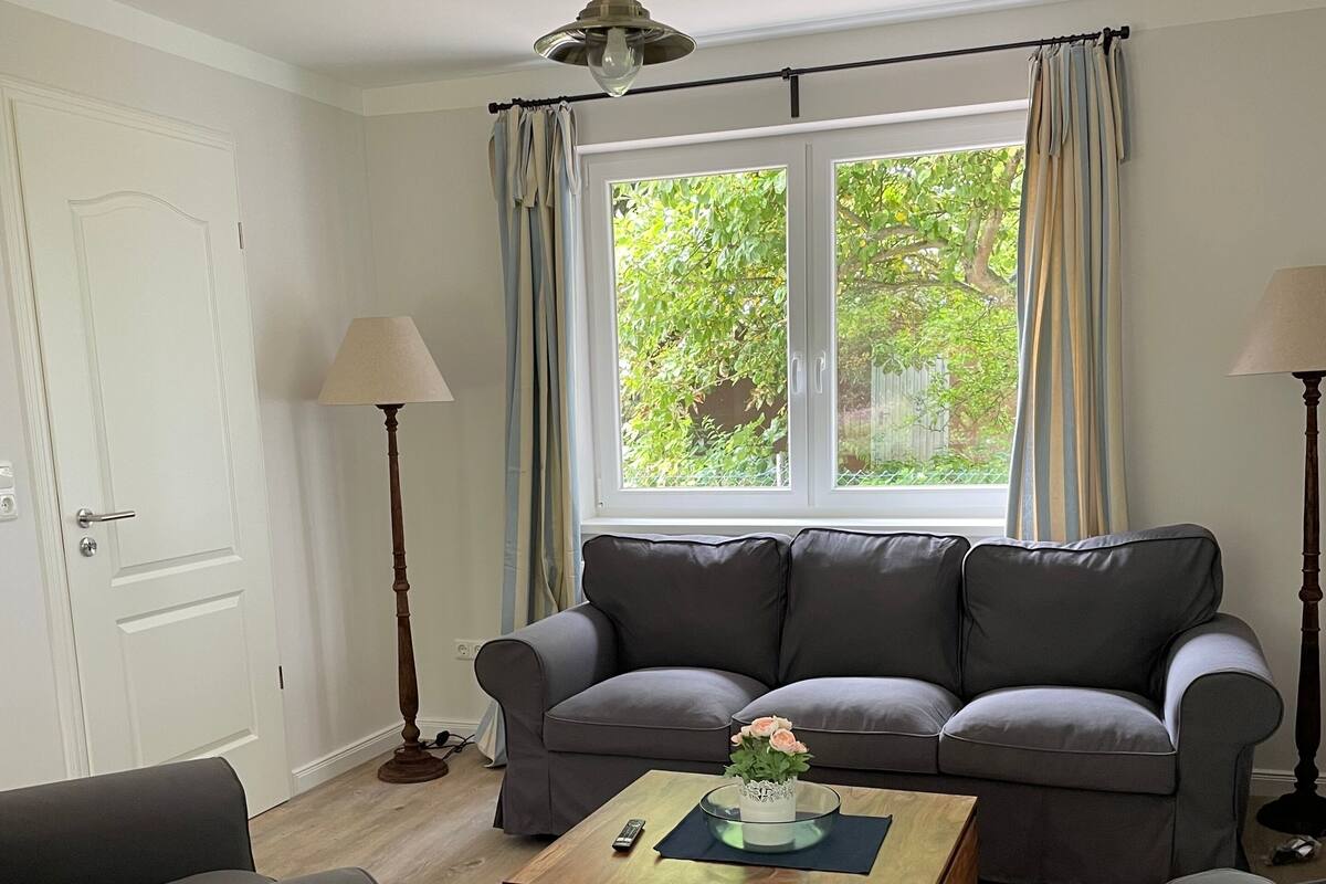 Un salon avec un canapé gris, une table basse en bois et deux lampadaires.