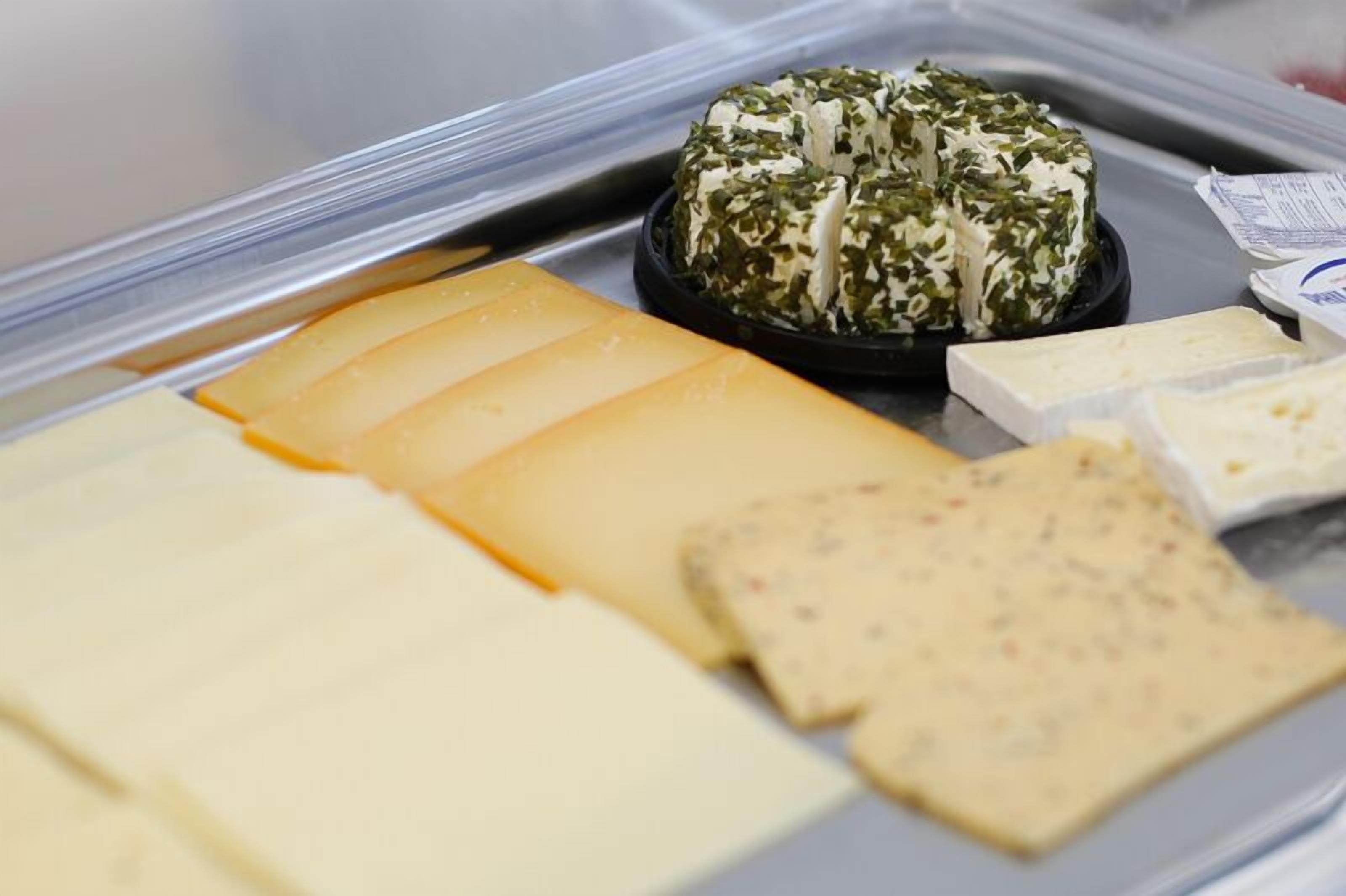 A variety of cheeses in a display case.