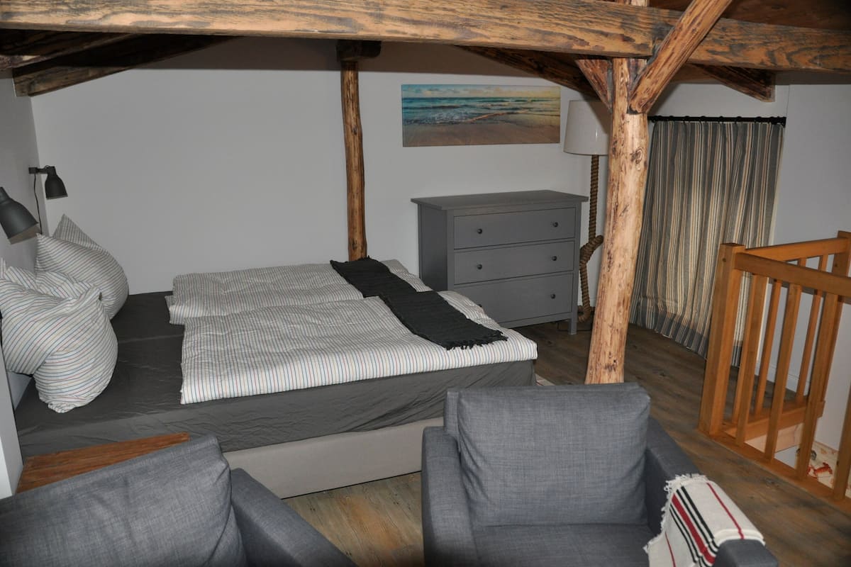 Une chambre à coucher comprenant un lit, une commode, une chaise et une structure de plafond en bois.