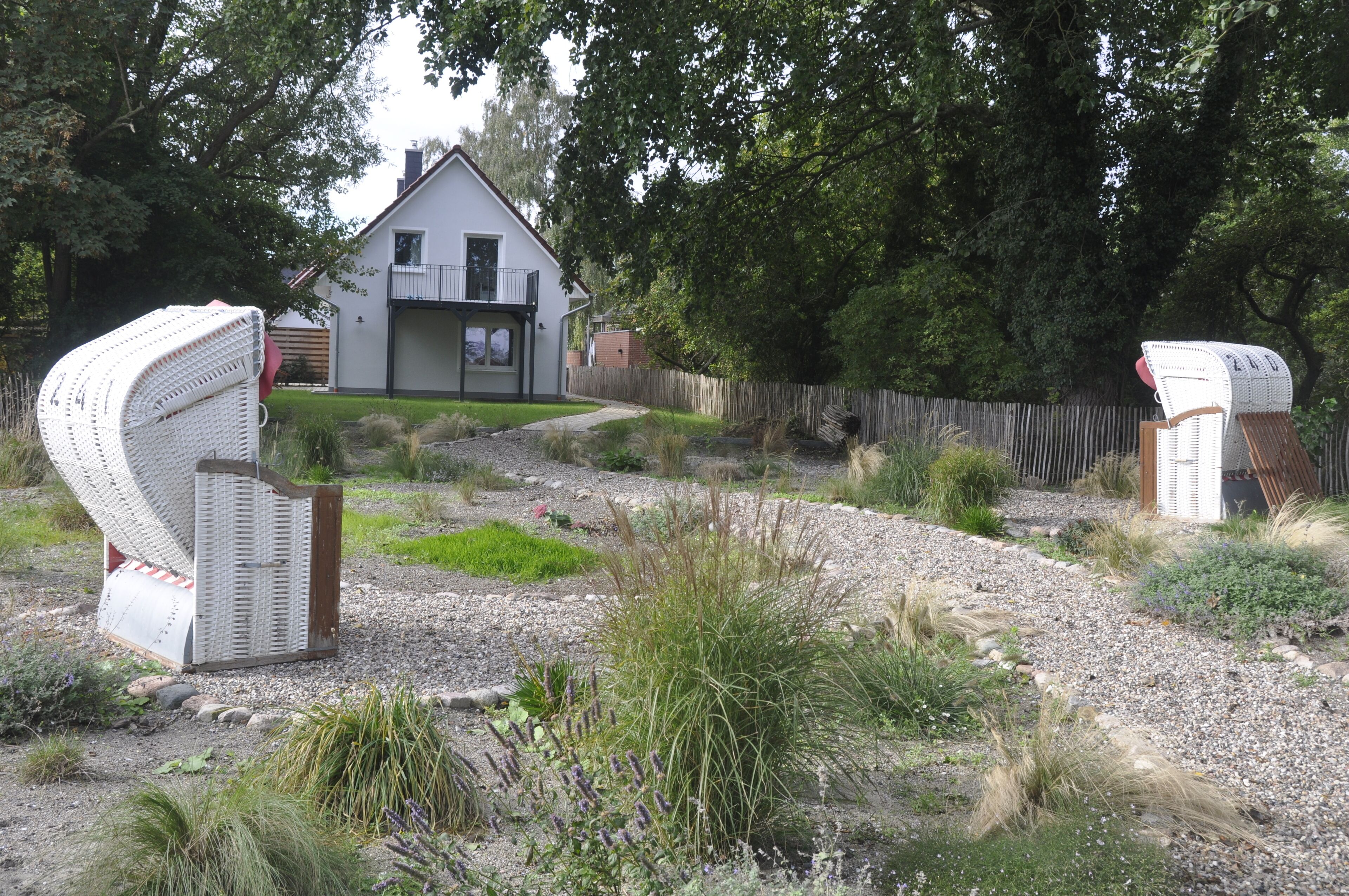 A house with a fenced yard, a gravel path, and two large white structures resembling storage units.