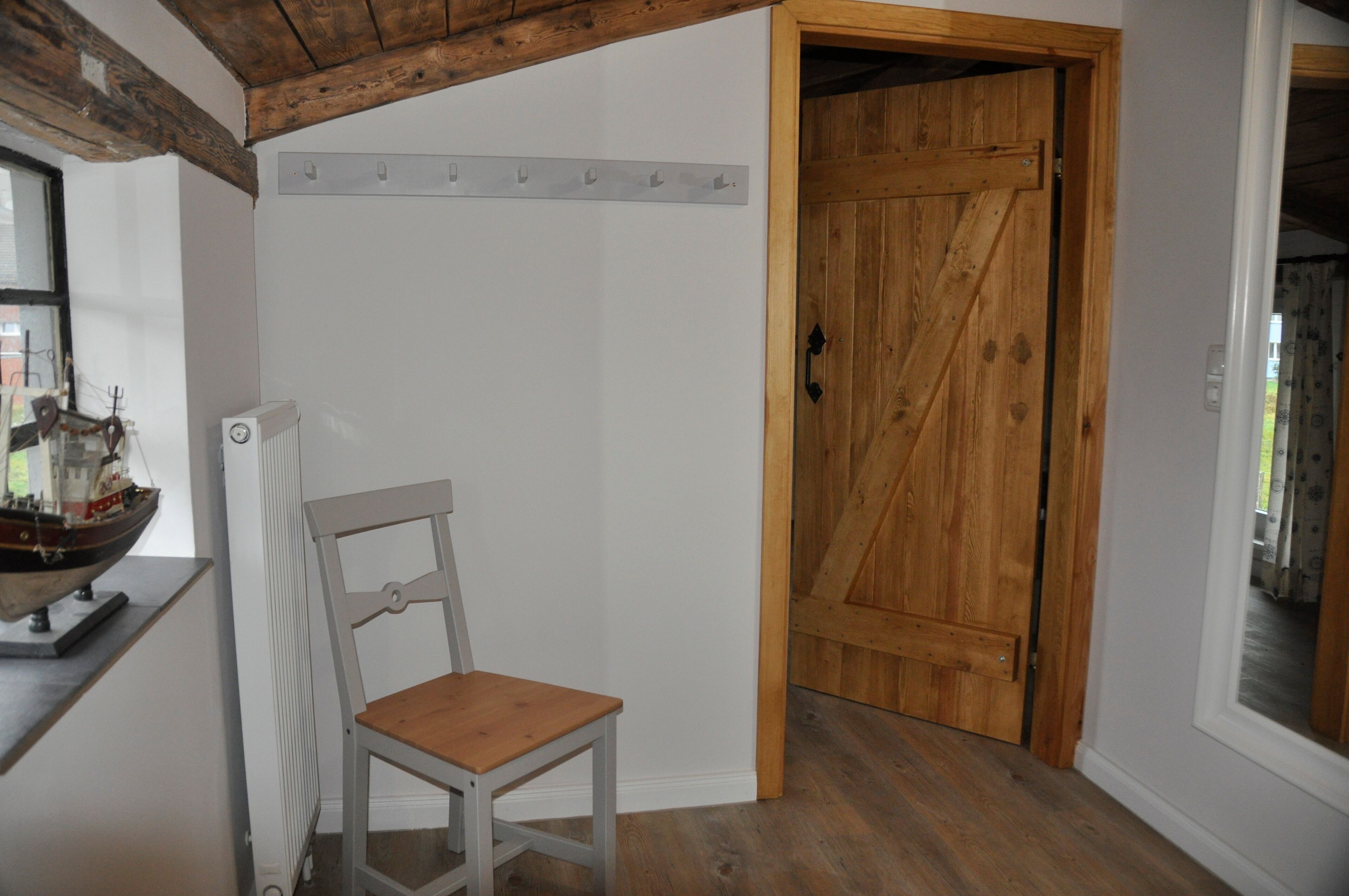 A room with a wooden door, a white radiator, and a wooden chair.