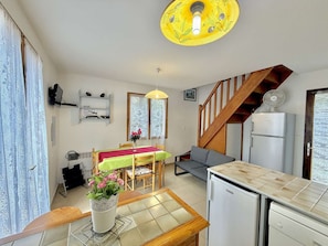 Un espace de vie compact comprenant un coin repas, une kitchenette, un escalier et un luminaire au plafond.