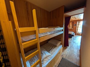 A bunk bed room with wooden walls and a view of another room with a bed and curtains. - Ski-In Studio - Balcony - Sleeps 4 (Montgenèvre)