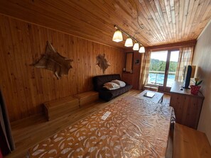 A room with wooden walls, a sofa, a bench, a table, and a view of a body of water. - Ski-In Studio - Balcony - Sleeps 4 (Montgenèvre)