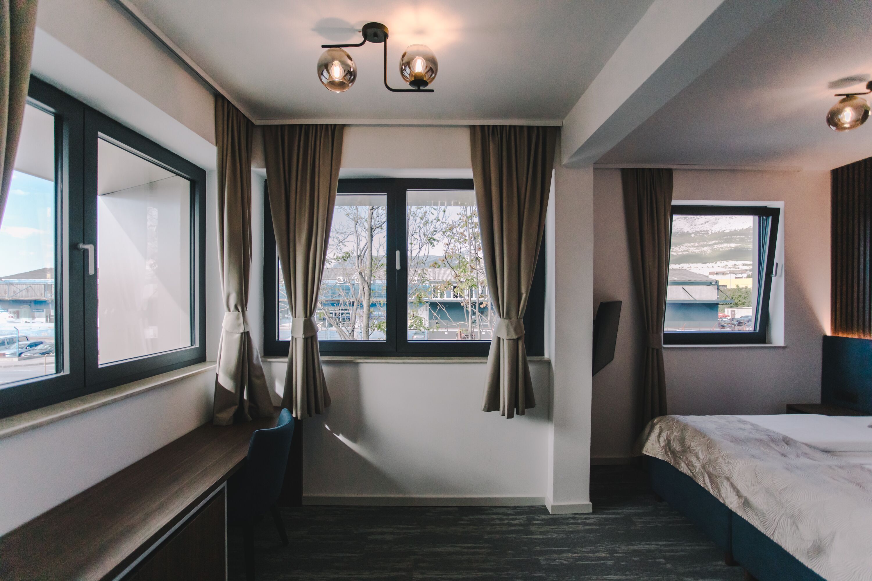 Una habitación de hotel con cama, escritorio y ventana con cortinas.