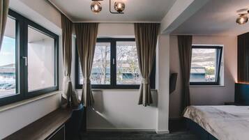 Una habitación de hotel con cama, escritorio y ventana con cortinas.