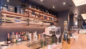 Un espace bar avec des étagères remplies de bouteilles d’alcool, de verres et une machine à café.