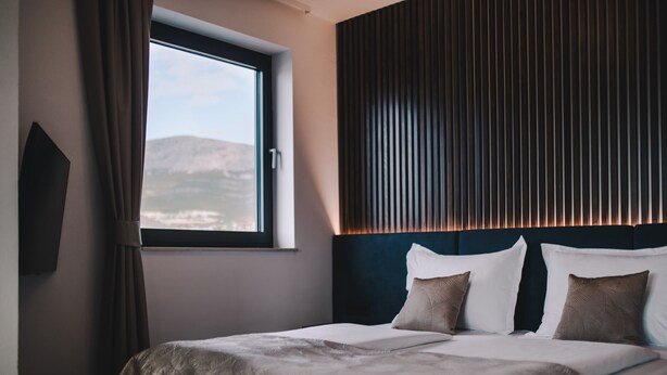 Une chambre d’hôtel avec un grand lit, une fenêtre avec des rideaux et une vue sur les montagnes.