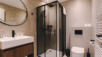Une salle de bain moderne avec une douche à parois de verre, un lavabo blanc avec un meuble en bois et des toilettes avec un abattant blanc.