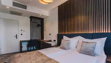 Habitación de hotel con una cama grande, un escritorio y una silla. Pared de paneles de madera y lámpara en el techo.