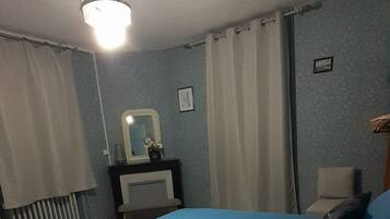 Et soveværelse med seng, natbord, spejl og radiator.