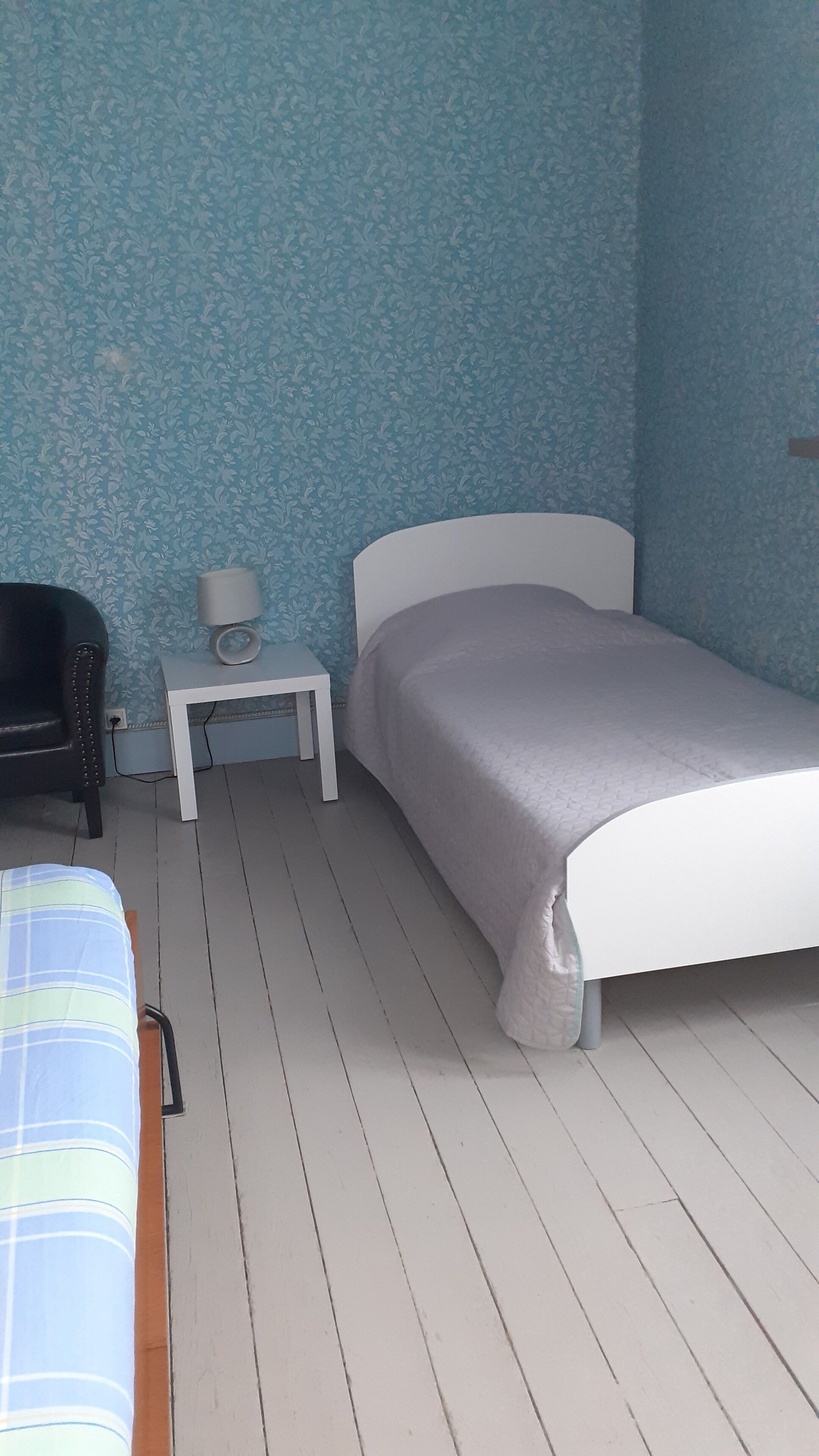 Une chambre à coucher avec un lit, une table de chevet, une lampe et une chaise.