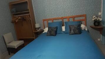 Un dormitorio con una cama, un armario de madera, una silla y una mesita de noche con lámpara.