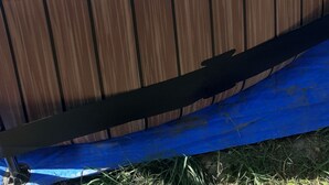 Une piscine hors sol en bois, avec un intérieur bleu, entourée d’une terrasse en bois et d’une clôture en bambou.